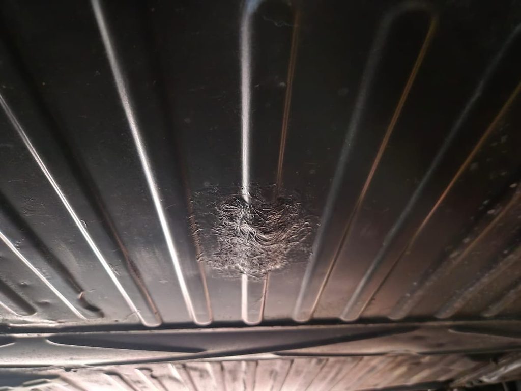Assoalho do Fusca visto por baixo, com remendo de fibra de vidro e resina entre as nervuras da chapa